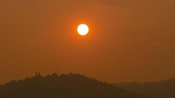 tid upphöra av de Sol miljö över kullar den där är täckt med moln, i de stil av smokey bakgrund. video