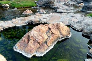 Rocks in the river covered with moss. at Chaeson Hot Spring. with a thin layer of steam. At Chae Son National Park Thailand. photo