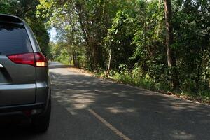 Car on the asphalt road in the forest with trees and nature background. Close-up on Tail light of car with turn on light signal. photo