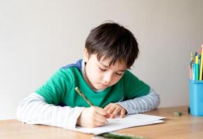 educación concepto,escuela niño utilizando negro color bolígrafo dibujo o dibujar en papel, retrato chico emplazamiento en mesa haciendo deberes en vivo habitacion,niño disfrutar Arte y arte actividad a hogar foto