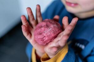 niño teniendo divertido modelado sal masa, auténtico actividad con natural rosado colorante remolacha jugo, multa motor habilidades desarrollo foto