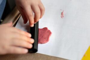 niño teniendo divertido modelado sal masa, auténtico actividad con natural rosado colorante remolacha jugo, multa motor habilidades desarrollo foto