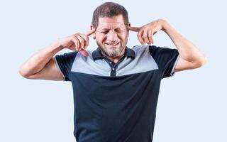 Displeased senior man covering his ears isolated. Older people ignoring and covering ears photo
