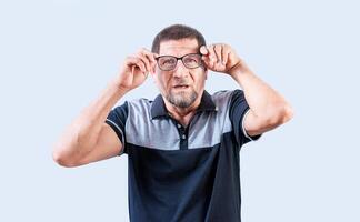 Surprised senior man taking off glasses looking at camera. Amazed senior man taking off glasses isolated photo