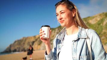 leende kvinna dricka kaffe i hämtmat kopp på strand video