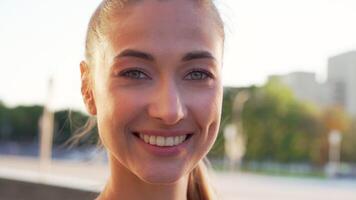 närbild porträtt av skön ung passa kvinna leende utomhus video