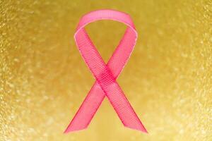 Pink ribbon for breast cancer awareness, symbolic bow color raising awareness on people living with women's breast tumor illness. bow isolated with clipping glitter gold background photo