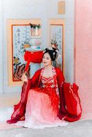 mujer vestir China nuevo año. retrato de un mujer. persona en tradicional traje. mujer en tradicional traje. hermosa joven mujer en un brillante rojo vestir y un corona de chino reina posando foto