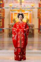 mujer vestir China nuevo año. retrato de un mujer. persona en tradicional traje. mujer en tradicional traje. hermosa joven mujer en un brillante rojo vestir y un corona de chino reina posando foto