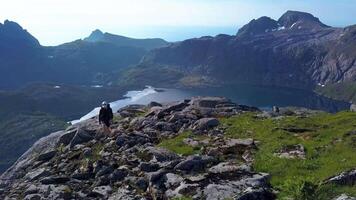 Aerial view of girl with a backpack goes on a mountain ridge. Beautiful view of the peaked tops of the Lofoten Islands. Norway 4k video