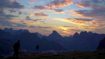 uma turistas apreciar uma lindo nascer do sol perto uma barraca dentro a montanhas. lindo Visão do a atingiu o pico tops do a lofoten ilhas. Noruega 4k video