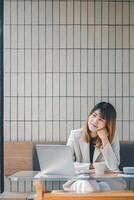 persona de libre dedicación concepto, alegre joven mujer de negocios disfrutando un descanso con un ordenador portátil a un cafetería, exhibiendo un relajado trabajo ambiente. foto