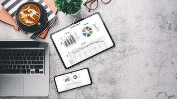 Modern office desk workplace with blank screen digital tablet and smartphone, laptop, eyeglass, notebook and cup of coffee, Top view flat lay with copy space. photo