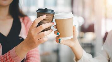 Business relax concept, A close-up shot capturing the hands of two businesswomen holding takeaway coffee cups during a coffee break at work. photo