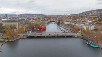 Antenne Aufnahmen hyper Ablauf von das Zürich alt Stadt, Dorf wo das limmat Fluss schließt sich an See Zürich mit Straßenbahn Laufen auf ein Brücke im Schweiz größten Stadt. Antenne Aussicht Drohne von Zürich Stadt. video