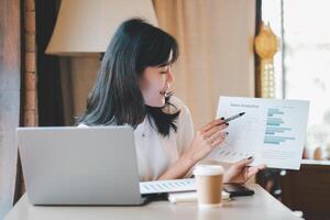 Business freelance concept, Professional Asian businesswoman discussing sales analytics report during a video call at a cafe. photo