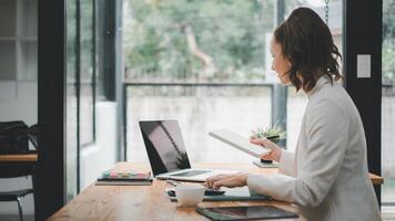 un enfocado mujer de negocios se involucra en multitarea a un bien organizado hogar oficina espacio, ejemplificando moderno remoto trabajar. foto