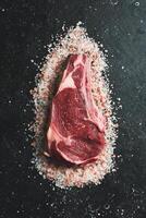 Dry-aged Raw cowboy on the bone beef meat Steak. On a black stone background. Top view. photo