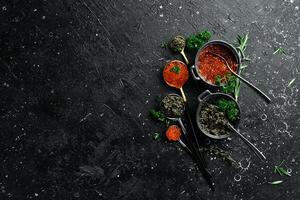 Set of red and black caviar in bowls. Premium caviar of high quality. On a black stone background. Top view. photo