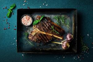 Healthy lean grilled medium-rare beef steak. T-bone steak in a metal baking dish. Rosemary and spices. photo