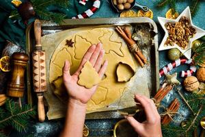 Navidad horneando concepto. hembra manos cortar fuera galletas desde el masa. ingredientes para horneando pan de jengibre. foto