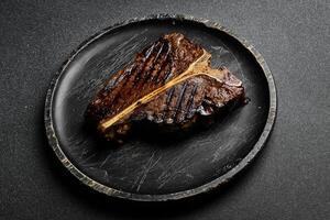 Grilled T-bone steak. Beef steak on a wooden black plate. Meat. photo