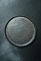 Empty gray plate ceramic on a dark gray background. Free space for text. Top view. photo