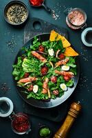 Fresh healthy salad. Salad with arugula, salted salmon, avocado, quail eggs and mushrooms. In a black plate. Diet food. photo