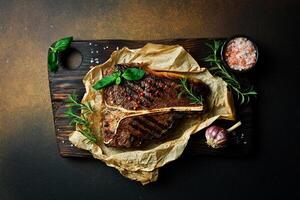 T-bone steak with rosemary on parchment paper. Beef steak on a dark background. Meat. photo