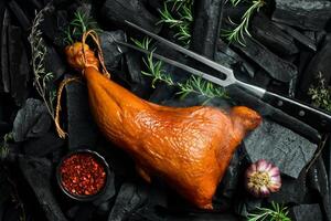 Smoked chicken thigh with spices on a stone background. On a black stone background. Free space for the recipe. photo