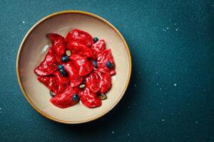 Dumplings with cherries, raspberries and salted caramel. On a black stone background. In a plate, close-up. photo