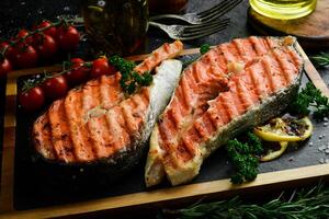 Grilled salmon steak with spices and vegetables. On a black background. Photo for the menu.