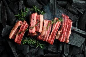 Fresh raw veal ribs with rosemary, on coals. Meat preparation, barbecue. Free space for text. photo