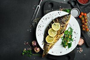 Baked carp fish with lemon and herbs. Barbecue menu. Free space for text. Close up. photo