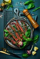 Cooked octopus tentacles with garlic and basil. Delicious healthy traditional food closeup served for lunch in modern gourmet cuisine restaurant. photo