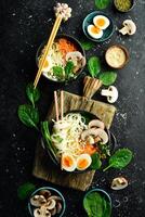 Japanese traditional udon noodles. Bowl of noodles with egg, mushrooms, green onions. On a black background. Top view. photo