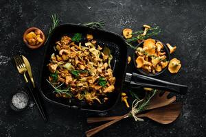 Chanterelle mushrooms fried with onions and spices in a pan on the kitchen table. Top view. Free space for text. photo