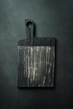 cocina Clásico de madera corte tablero. marrón tablero. cocina utensilios en un oscuro antecedentes. foto