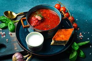 Homemade borsch with sour cream. Beet soup. Ukrainian cuisine. Close up. On a dark stone background. photo