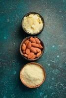 Almonds and almond flour in bowls. On a dark textured background. Copy space. photo