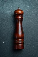 Wooden pepper mill. On a black slate background. Top view. photo
