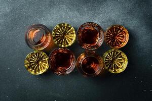 Strong alcoholic drinks, hard liquors, spirits and distillates on a stone table. Strong aged alcoholic drinks. On a dark stone background. photo