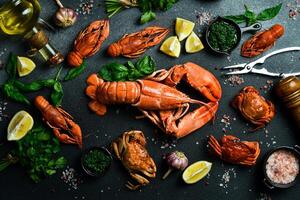 grilled lobster with lemon and basil on a black slate board. on a dark wooden table photo