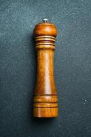 Wooden pepper mill. On a black slate background. Top view. photo