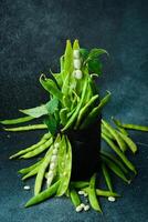young green beans and Pods of beans on a gray old background. Dark rustic style, side view. photo