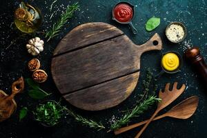 Cooking background. Kitchen board, vegetables and spices. On a black stone background. Top view. photo