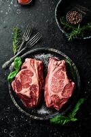Raw organic marbled beef steaks with spices. On a dark background. Meat. Free space for text. photo