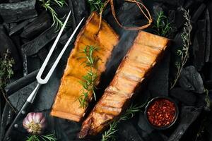 Smoked pork ribs with spices on a stone background. On a black stone background. Free space for the recipe. photo