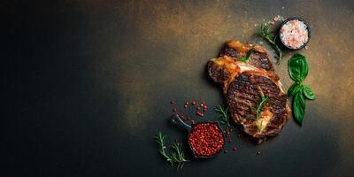 Grilled veal steak with rosemary on a dark brown background. Banner photo. Top view with copy space. Flat lay photo