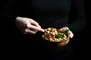 A bowl of hazelnuts in the hands of a woman. Healthy high-calorie vegan food concept. Close up. photo